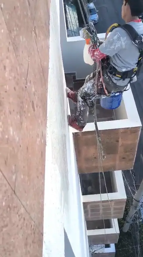 Vistas desde azotea del operario con arnés y cuerdas junto a la fachada y los balcones.