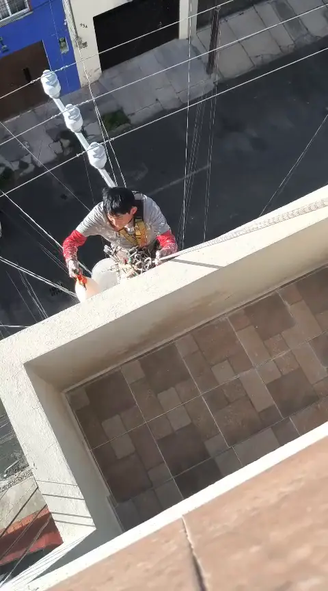 Vista desde arriba del operario suspendido junto al borde exterior de un balcón.